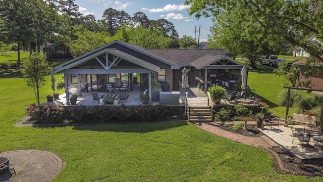 back of house with a lawn, a shingled roof, brick siding, and a patio area