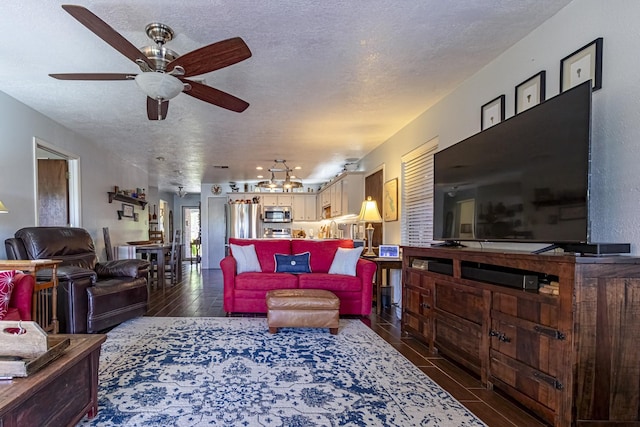 living area featuring ceiling fan, a textured ceiling, and dark wood-style floors
