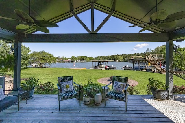 deck with a water view, a yard, and ceiling fan