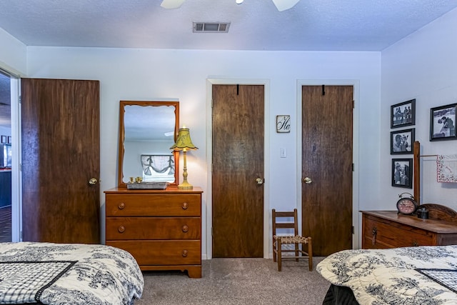 carpeted bedroom with two closets, visible vents, and ceiling fan