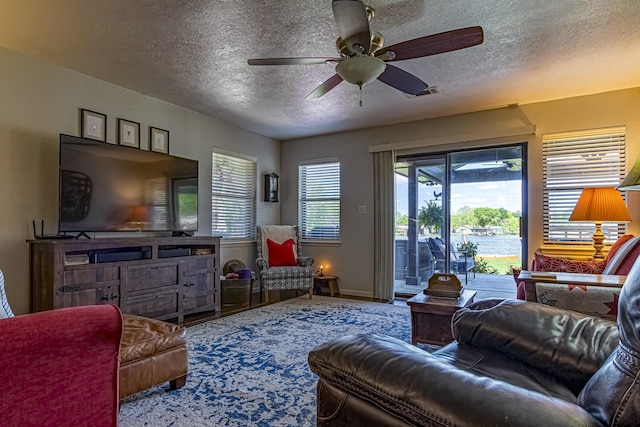 living room featuring baseboards, a ceiling fan, and a textured ceiling