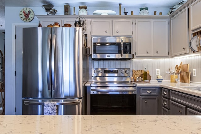 kitchen with gray cabinets, light stone counters, and stainless steel appliances