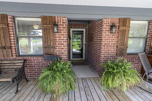 entrance to property with covered porch and brick siding