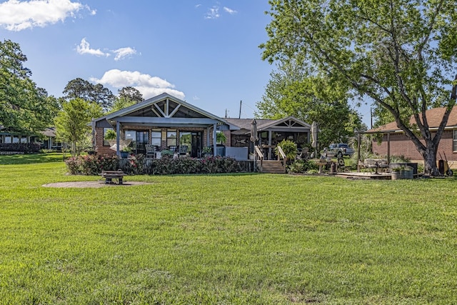 rear view of property featuring a yard and an outdoor fire pit