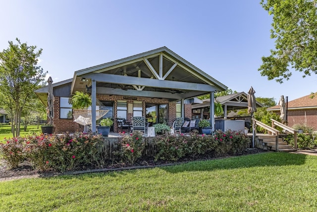rear view of property featuring a lawn, a gazebo, and brick siding