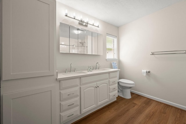 17311 Lowick St, Spring, TX 77379 - full bathroom featuring wood finished floors, baseboards, toilet, double vanity, and a textured ceiling