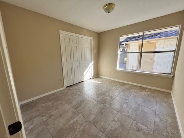 unfurnished bedroom with a closet and baseboards