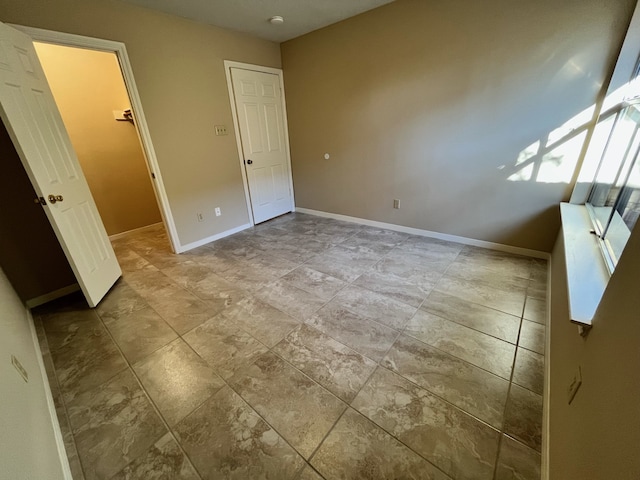 unfurnished bedroom featuring baseboards and a walk in closet