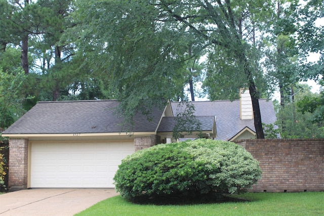 view of front facade featuring brick siding, an attached garage, a shingled roof, and driveway