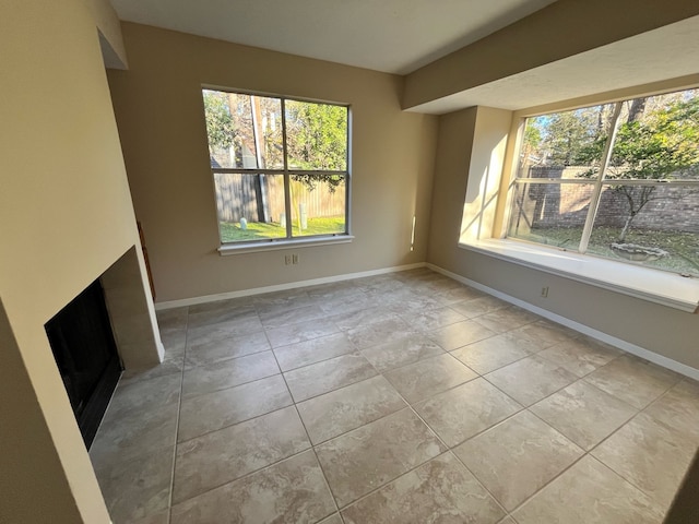 unfurnished living room featuring a fireplace, baseboards, and tile patterned flooring