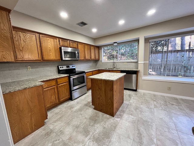 kitchen featuring a kitchen island, tasteful backsplash, brown cabinetry, and appliances with stainless steel finishes