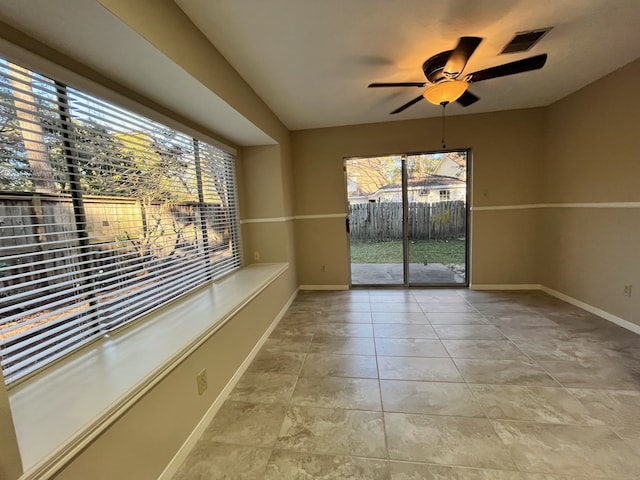 interior space featuring ceiling fan, baseboards, visible vents, and plenty of natural light