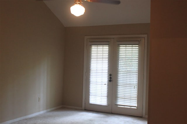 empty room featuring baseboards, ceiling fan, vaulted ceiling, french doors, and light colored carpet