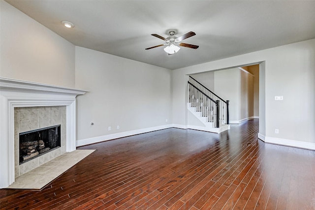 unfurnished living room featuring stairs, dark wood-style floors, baseboards, and a ceiling fan