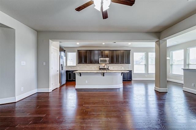 kitchen featuring a breakfast bar, light countertops, ceiling fan, stainless steel appliances, and a sink