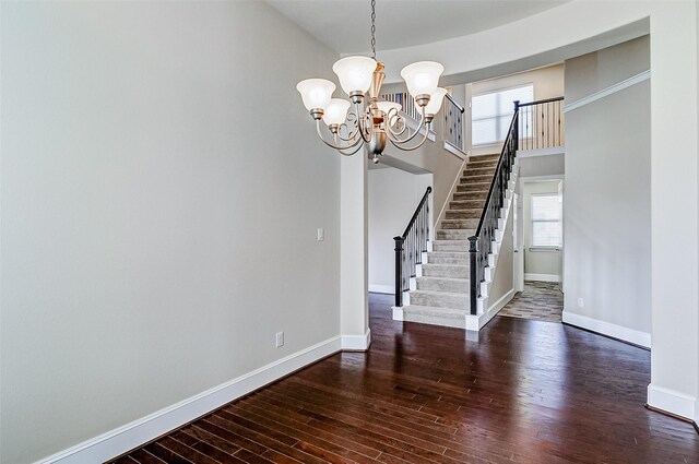unfurnished dining area with dark wood-type flooring, baseboards, stairs, and a notable chandelier