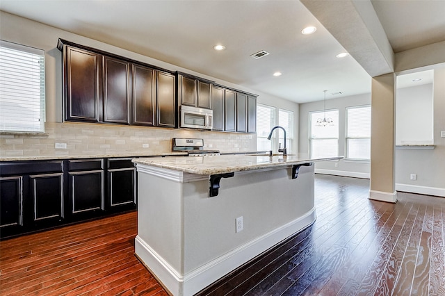 kitchen featuring tasteful backsplash, baseboards, a breakfast bar area, stainless steel appliances, and a sink