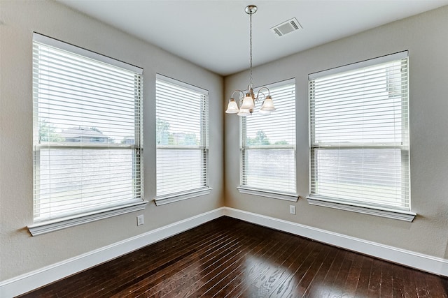 unfurnished dining area featuring a chandelier, baseboards, dark wood finished floors, and visible vents