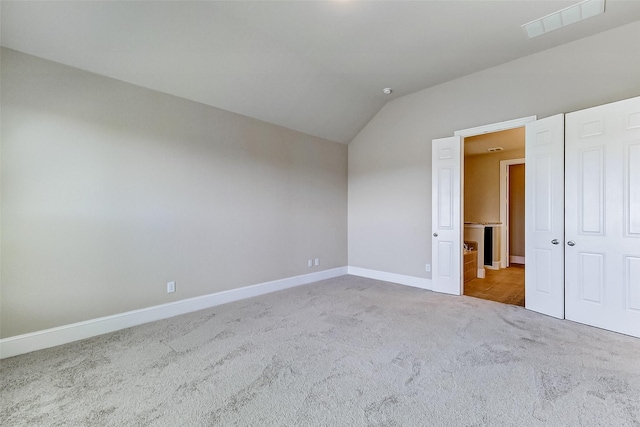 unfurnished bedroom featuring visible vents, baseboards, vaulted ceiling, and carpet