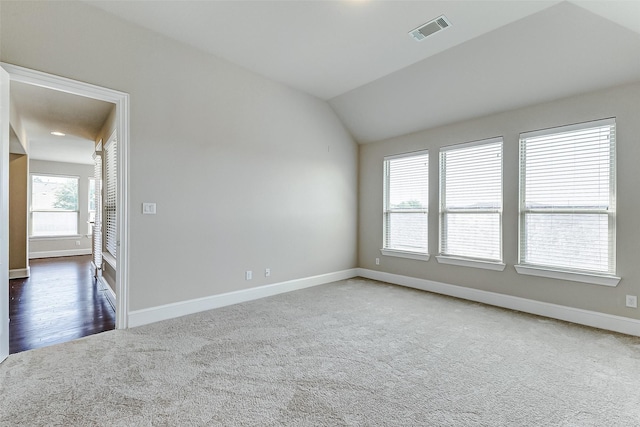 carpeted spare room with baseboards, vaulted ceiling, and visible vents