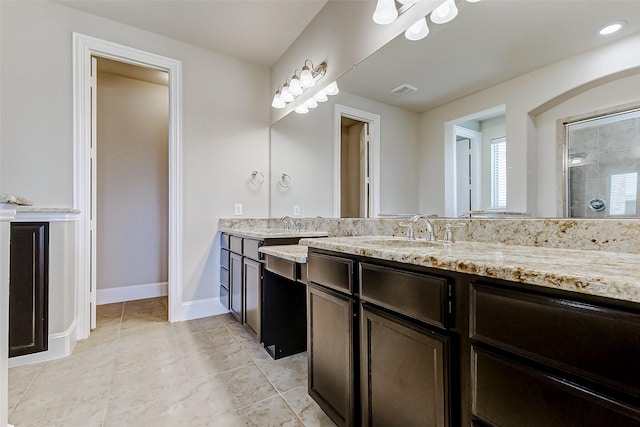 bathroom with tile patterned flooring, vanity, baseboards, and a tile shower