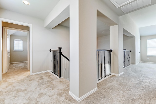 corridor with an upstairs landing, carpet flooring, visible vents, and a healthy amount of sunlight