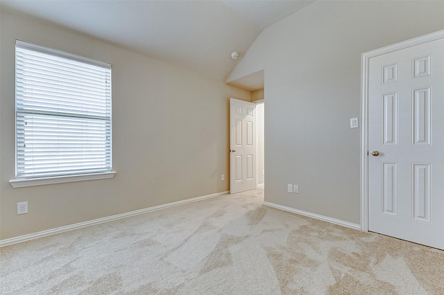 empty room with a wealth of natural light, carpet, baseboards, and lofted ceiling