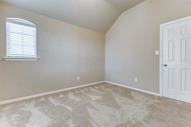 spare room with baseboards, vaulted ceiling, and carpet floors