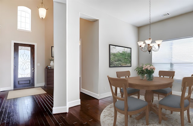 dining space with dark wood-style flooring, visible vents, baseboards, and an inviting chandelier