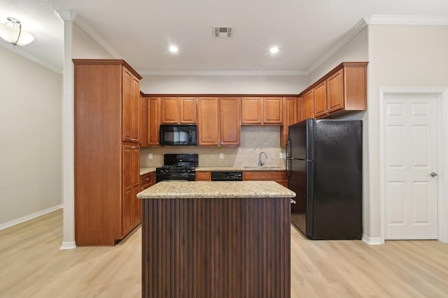 kitchen featuring tasteful backsplash, black appliances, a kitchen island, a sink, and light wood finished floors