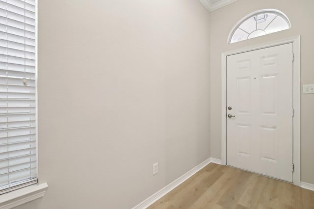 entryway with light wood finished floors, baseboards, and ornamental molding