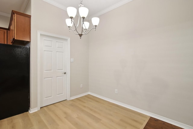 unfurnished dining area with ornamental molding, baseboards, an inviting chandelier, and light wood-style floors