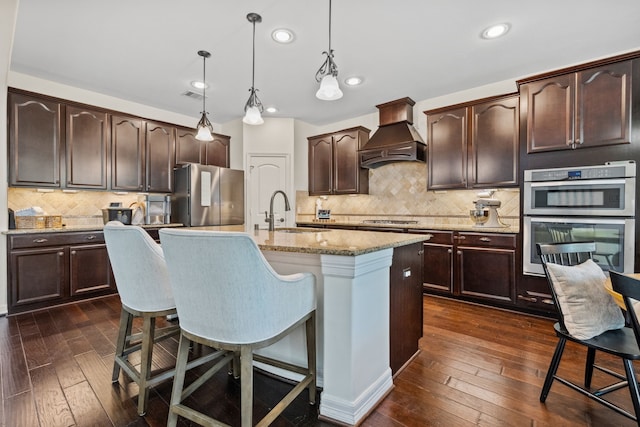 kitchen with visible vents, custom exhaust hood, appliances with stainless steel finishes, dark wood-style flooring, and a sink