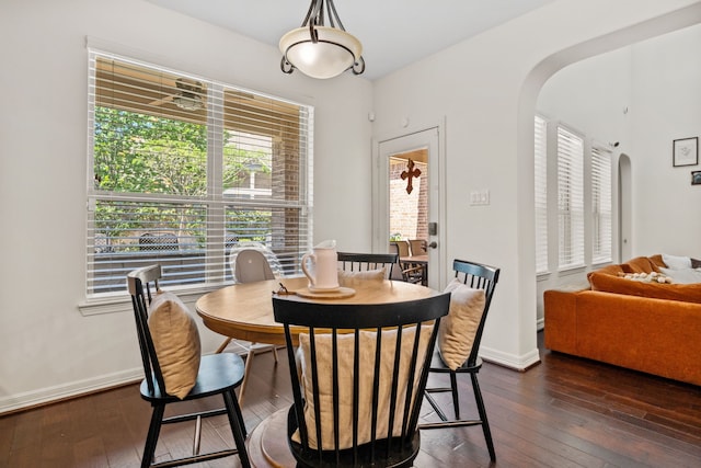 dining room with baseboards, arched walkways, and dark wood finished floors