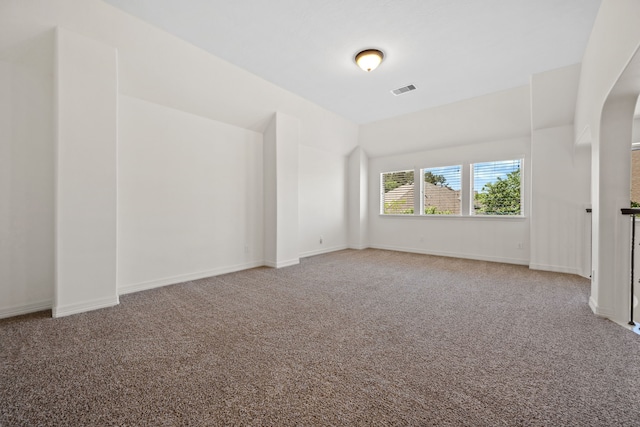 unfurnished room featuring visible vents, baseboards, arched walkways, and carpet