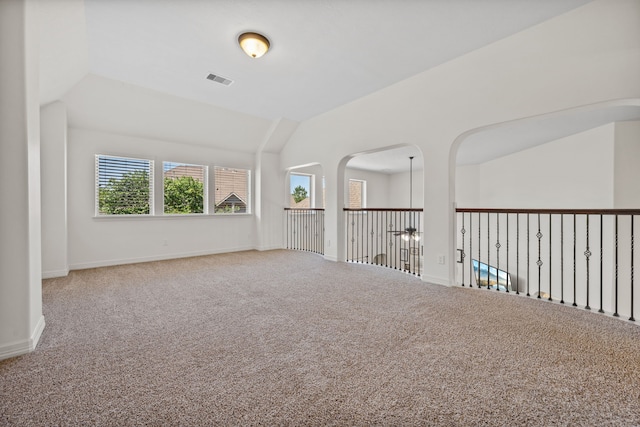 unfurnished room with visible vents, baseboards, lofted ceiling, and carpet floors