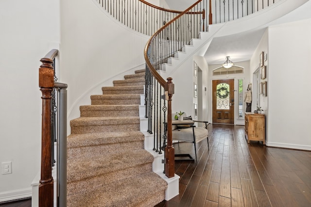 entrance foyer with a towering ceiling, dark wood finished floors, baseboards, and stairs