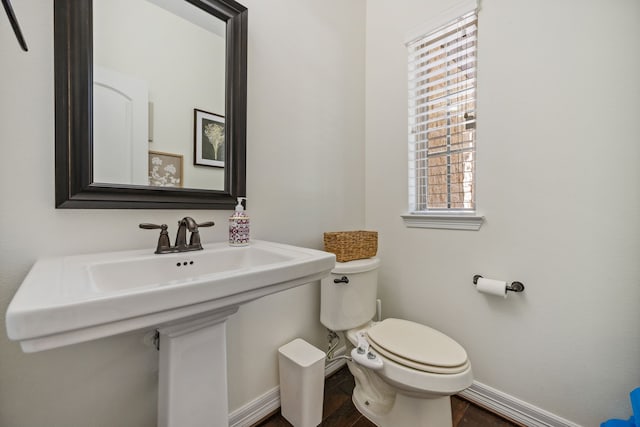 half bath featuring toilet, wood finished floors, and baseboards