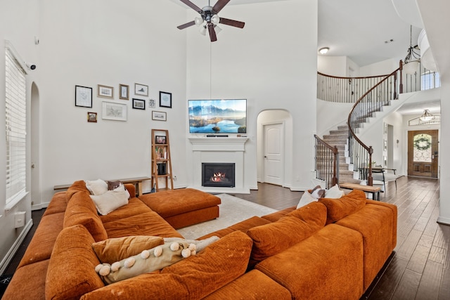 living room with ceiling fan, arched walkways, and a high ceiling