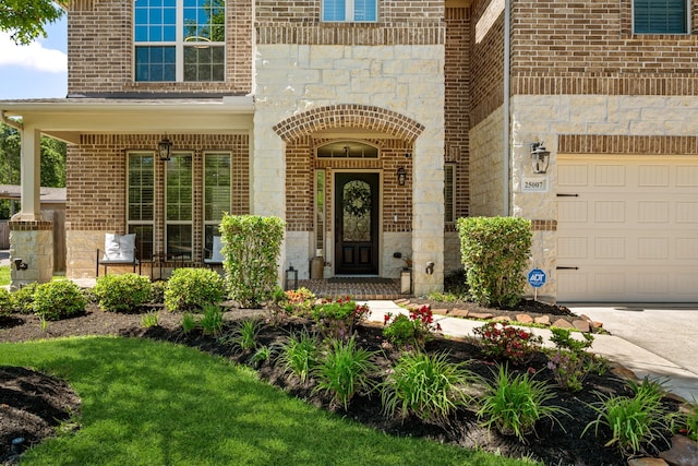 property entrance with a garage, brick siding, and stone siding