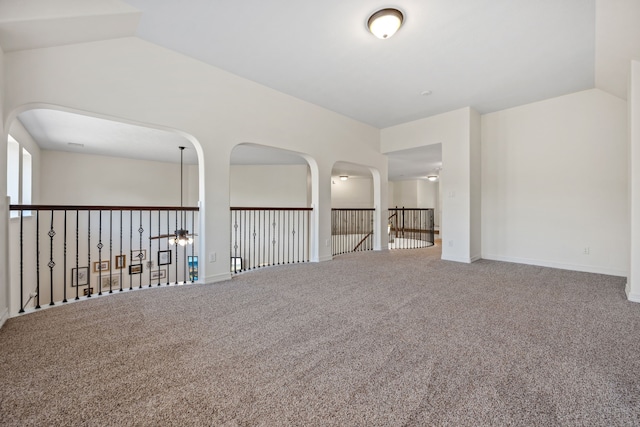 spare room featuring baseboards, carpet, and vaulted ceiling