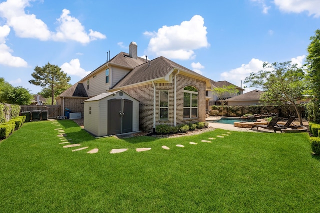 back of property with an outbuilding, a storage shed, a chimney, a fenced backyard, and brick siding
