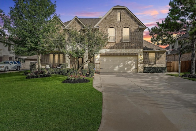 view of front of home featuring an attached garage, fence, brick siding, a front lawn, and driveway