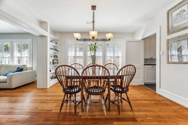 719 Key St, Houston, TX 77009 - dining space featuring built in features, light wood-style floors, a chandelier, and baseboards