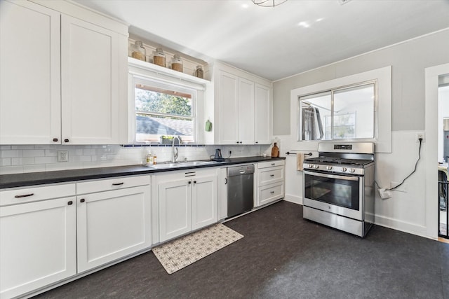 719 Key St, Houston, TX 77009 - kitchen featuring appliances with stainless steel finishes, a sink, dark countertops, white cabinetry, and decorative backsplash