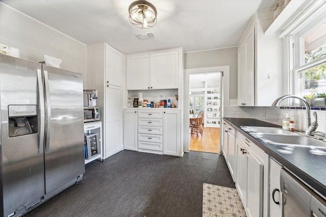 719 Key St, Houston, TX 77009 - kitchen featuring stainless steel appliances, a sink, white cabinetry, decorative backsplash, and dark wood-type flooring