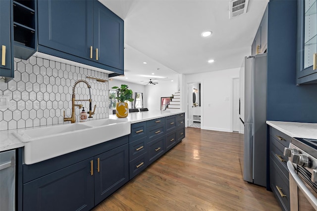 kitchen with visible vents, a sink, appliances with stainless steel finishes, decorative backsplash, and blue cabinets