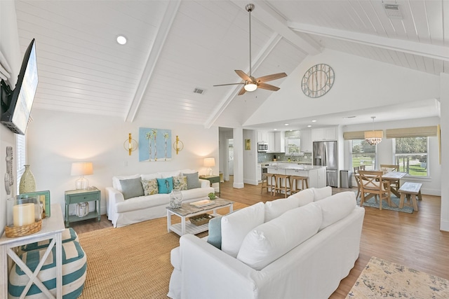 living area featuring light wood-style flooring, beamed ceiling, a ceiling fan, and visible vents