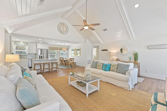 living room with beam ceiling, baseboards, light wood-type flooring, and visible vents