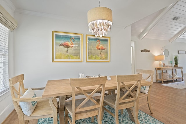 dining room featuring visible vents, ornamental molding, a chandelier, beam ceiling, and wood finished floors